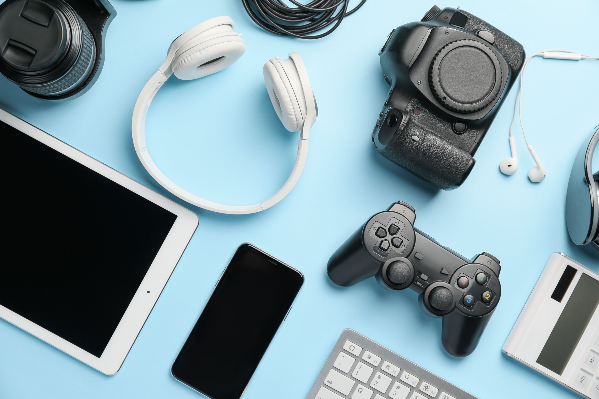 Assortment of modern digital gadgets and accessories on a bright blue background